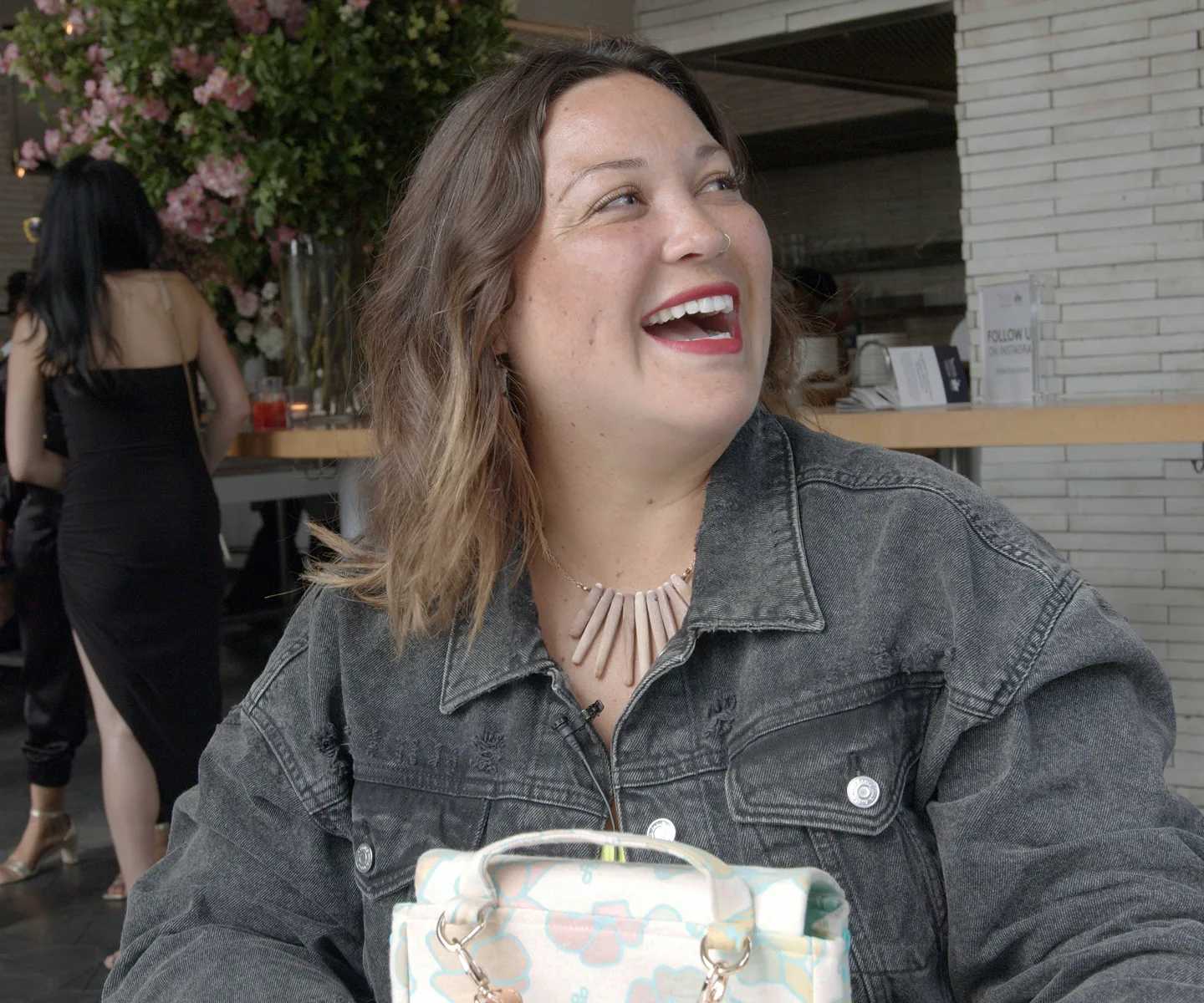 Woman smiling. She's seated at an outdoor café.