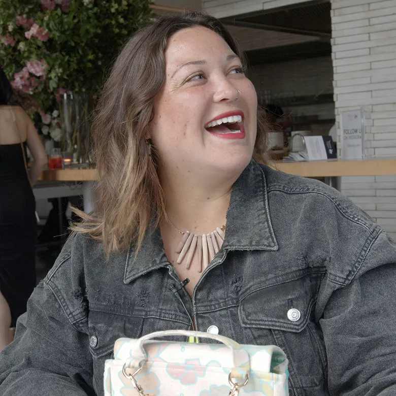 Woman smiling. She's seated at an outdoor café.