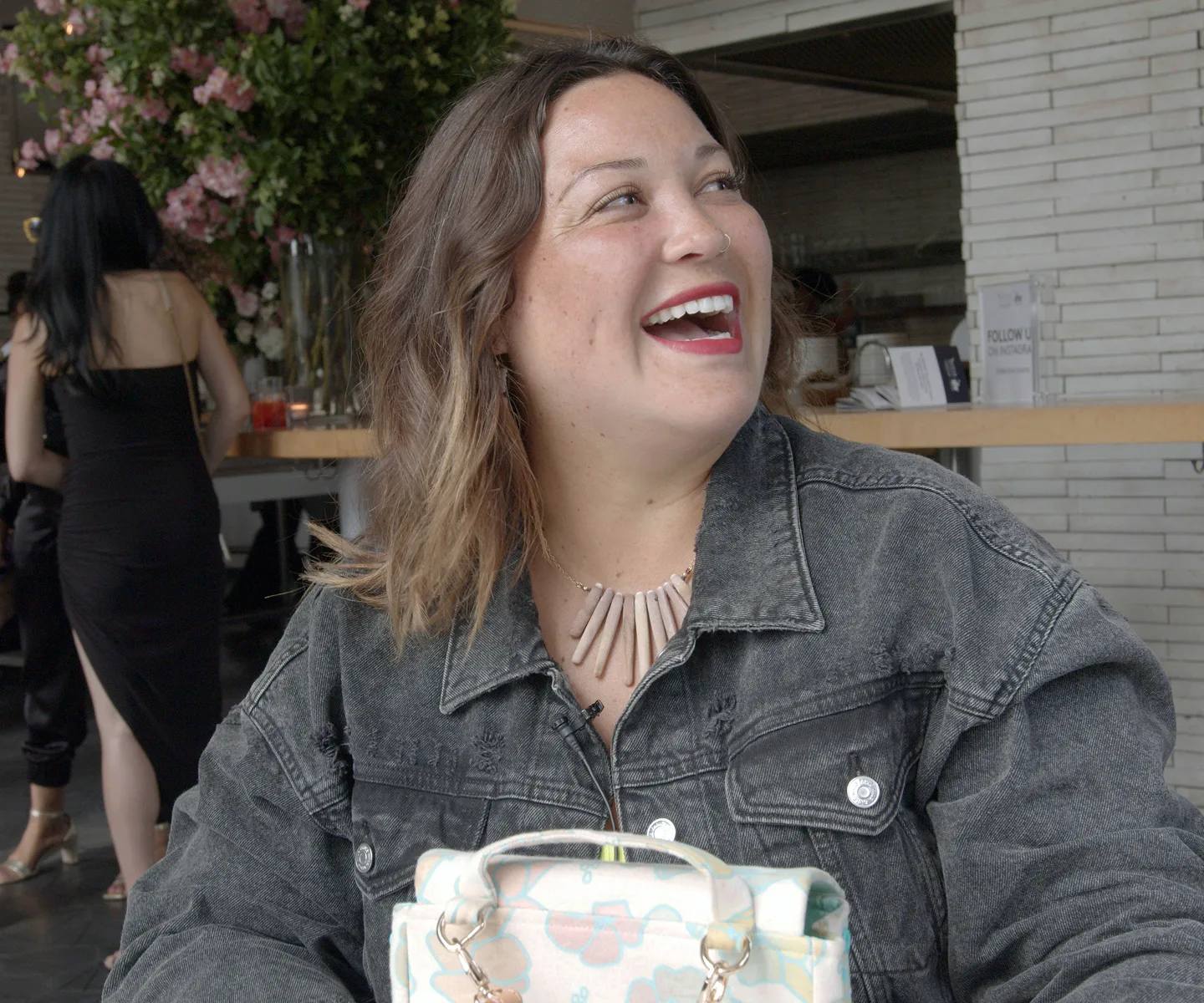 Woman smiling. She's seated at an outdoor café.