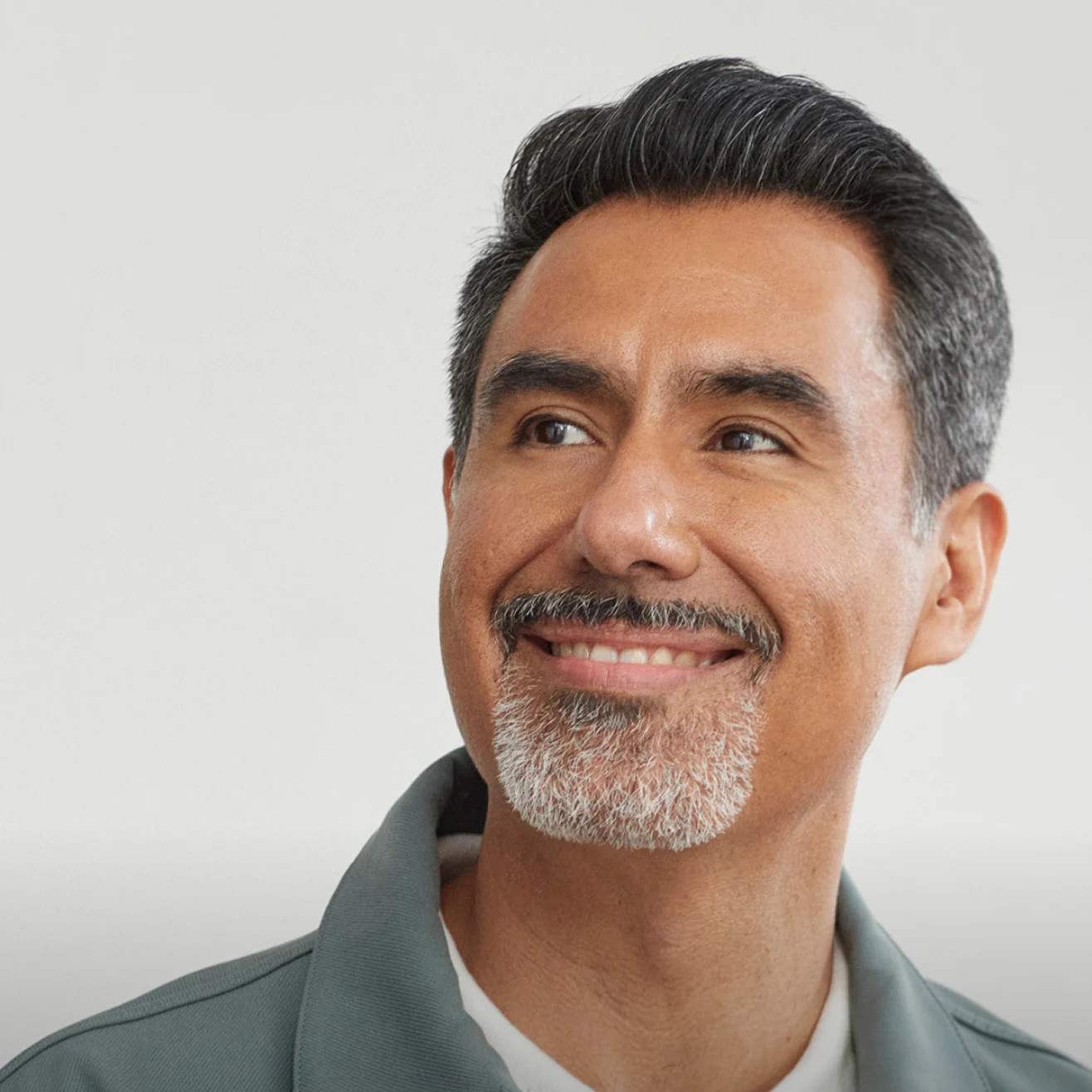 A man with a beard smiling and looking to the left